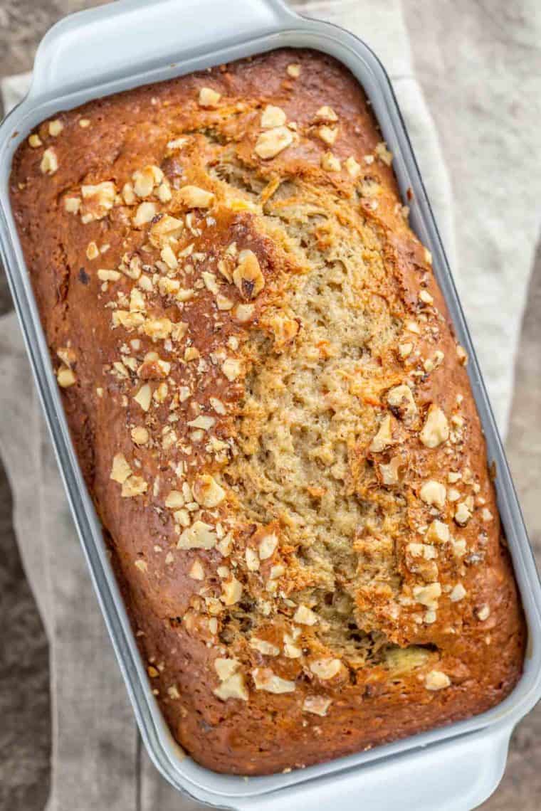 Banana carrot bread in a bread pan topped with chopped walnuts. 