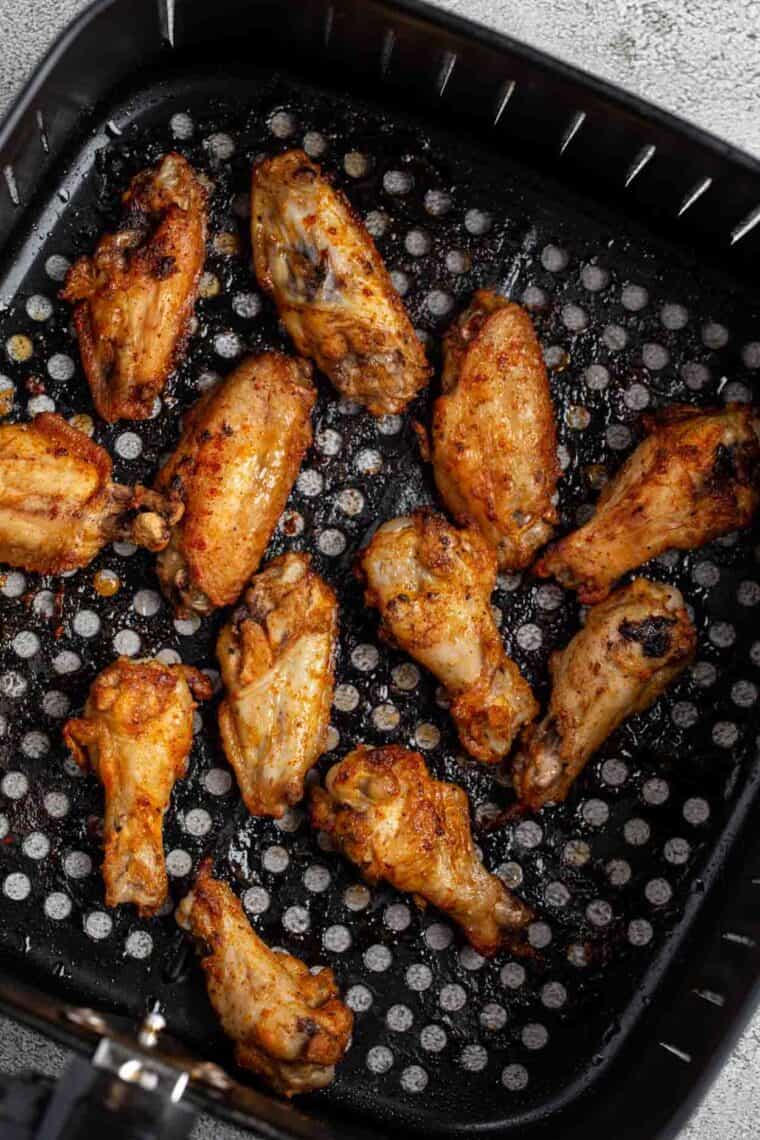 The air fryer basket with the baked wings.