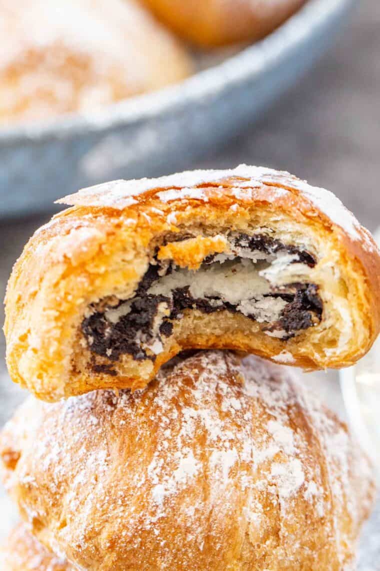 Air fried Oreo topped with powdered sugar bitten into showing the Oreo inside the crescent dough.