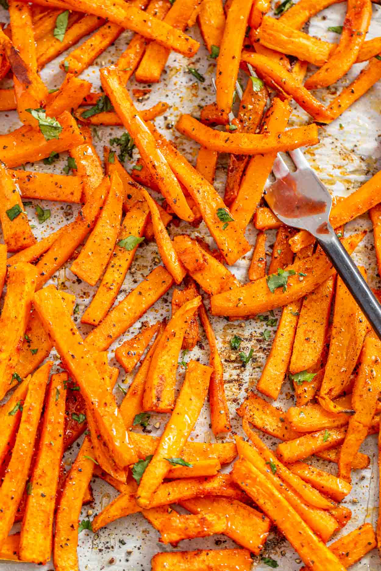Sweet potato fries on a baking with a fork. 
