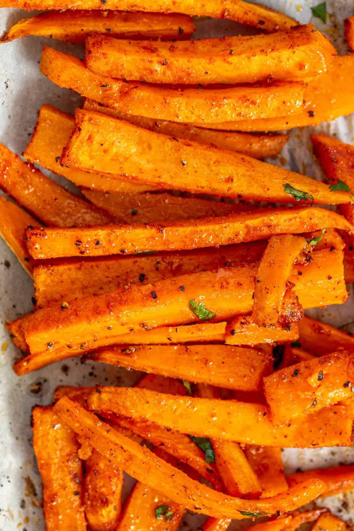 Sweet potato fries stacked in a row and topped with fresh cilantro.