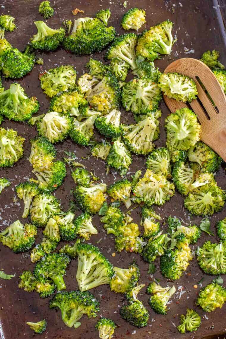 Crispy oven roasted broccoli florets topped with parmesan cheese on a baking sheet. 