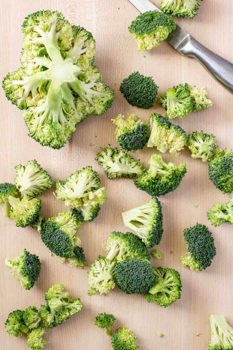 Broccoli floret and knife on a cutting board. 