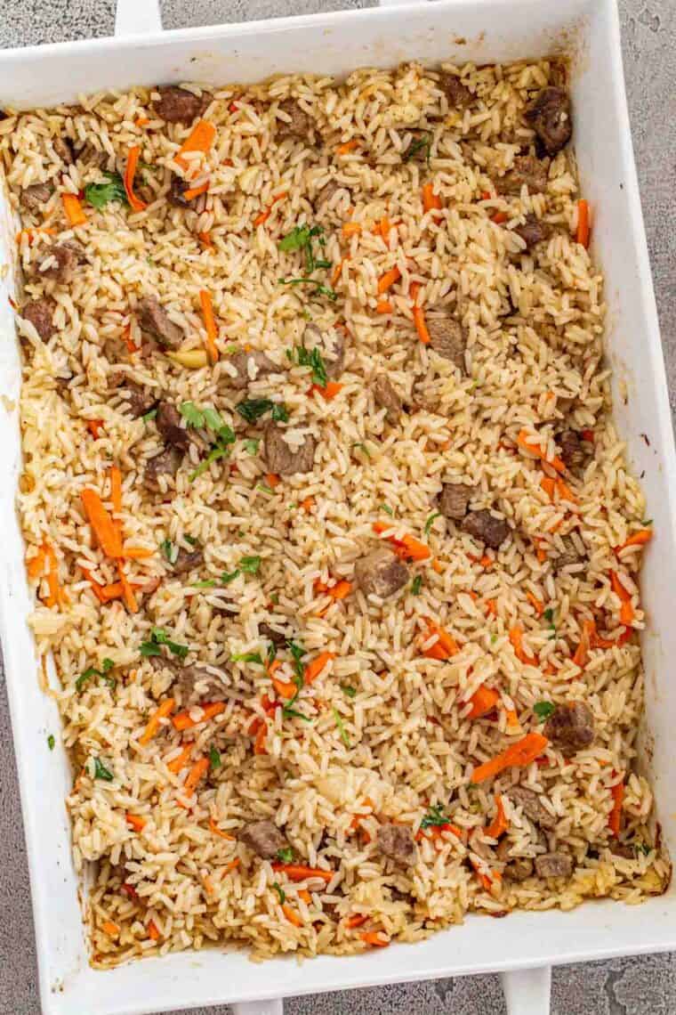 Baked rice pilaf recipe in a white casserole dish topped with fresh chopped cilantro.