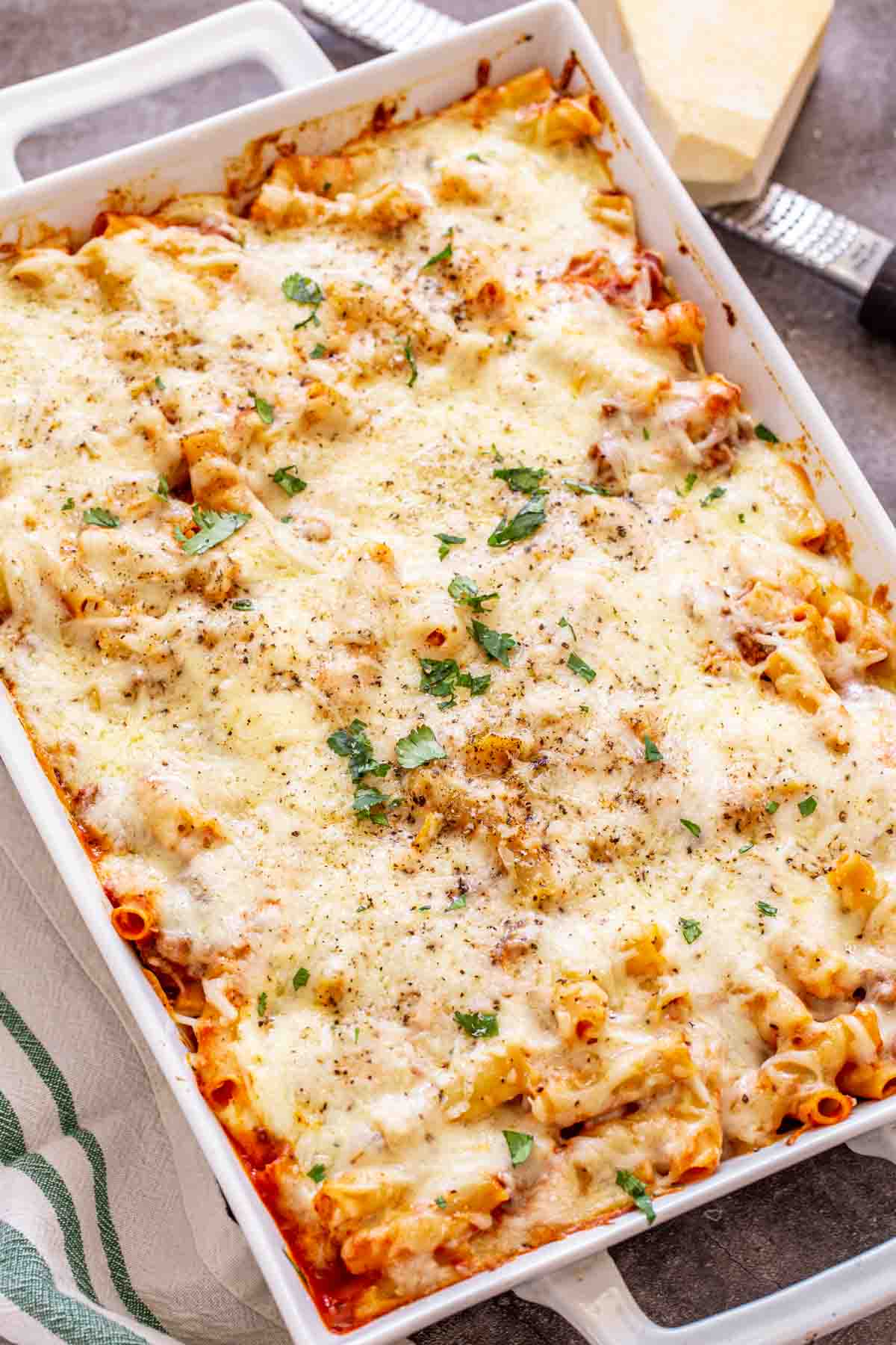 Baked ziti with ricotta cheese in a white casserole dish. 