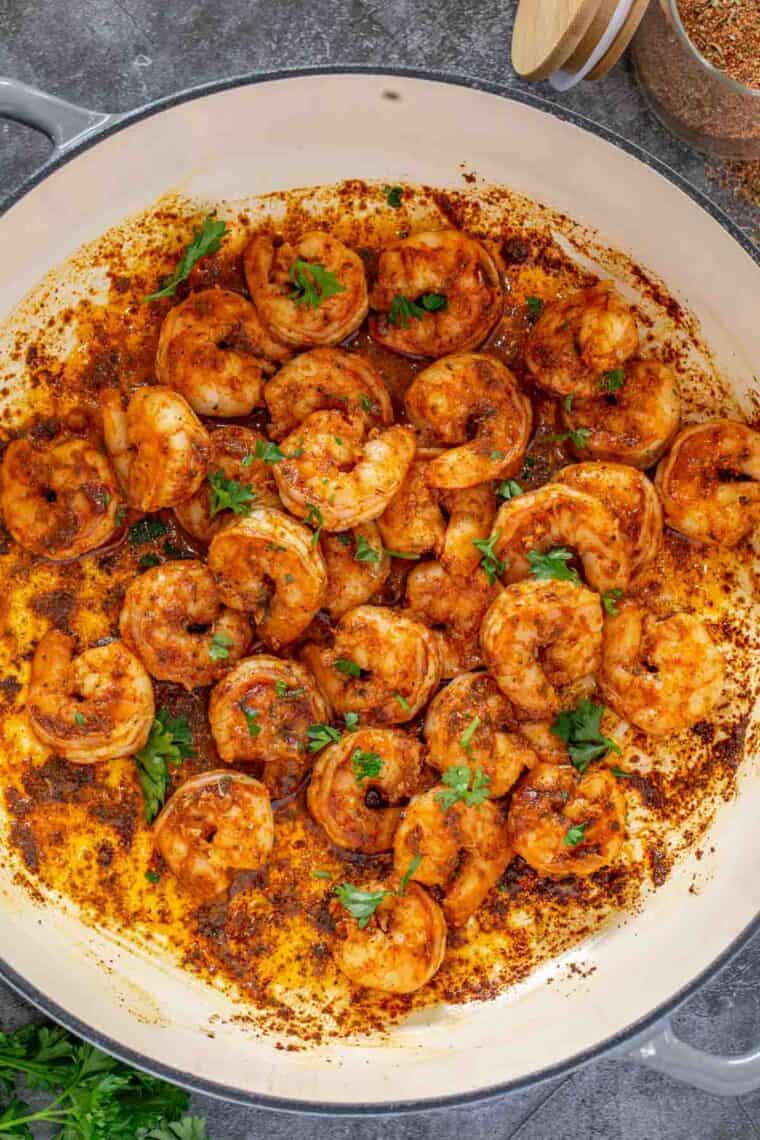 Cajun shrimp in a skillet topped with fresh chopped greens.
