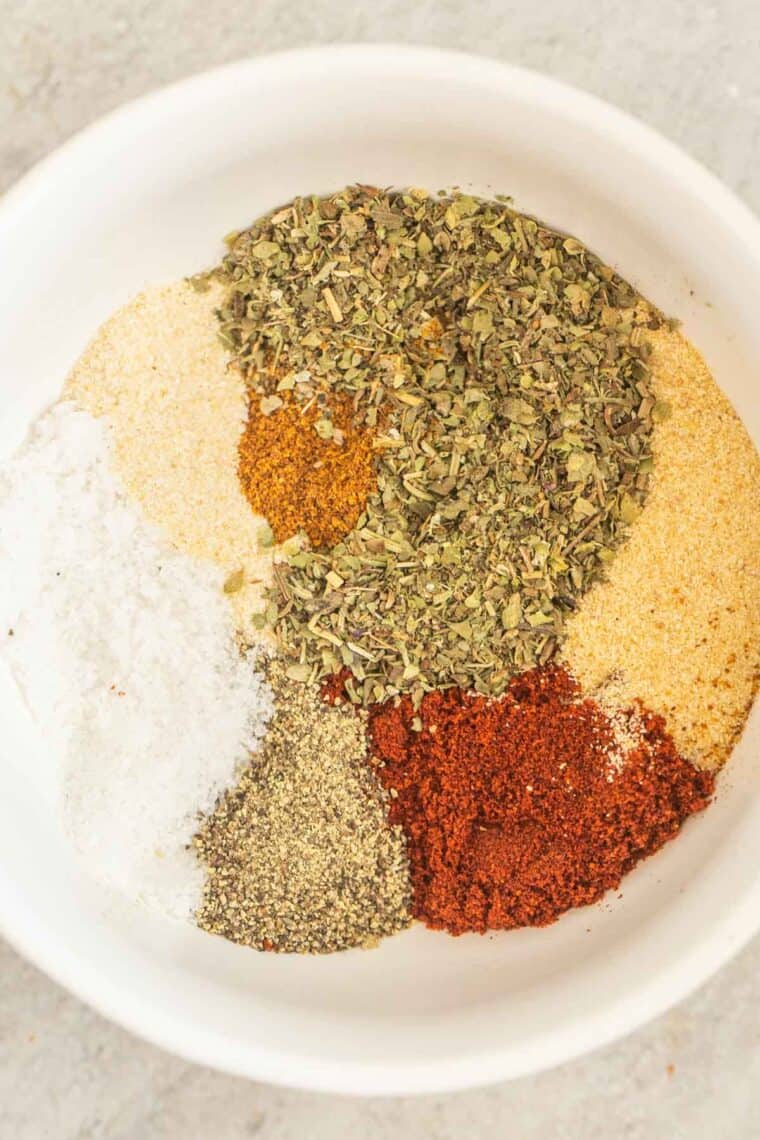 A white bowl of all the ingredients for homemade chicken seasoning. 