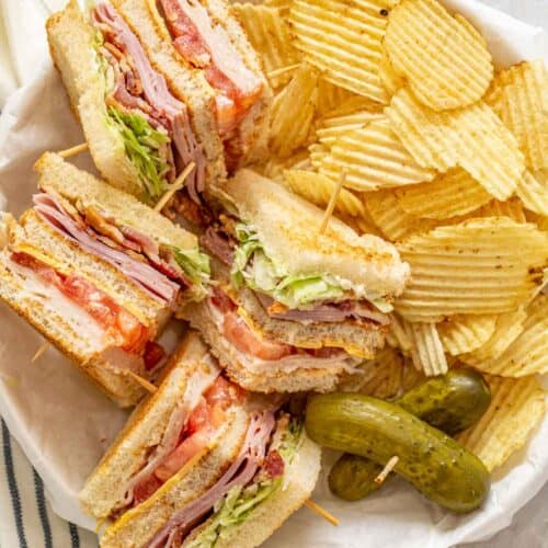 A plate with club sandwiches and potato chips.