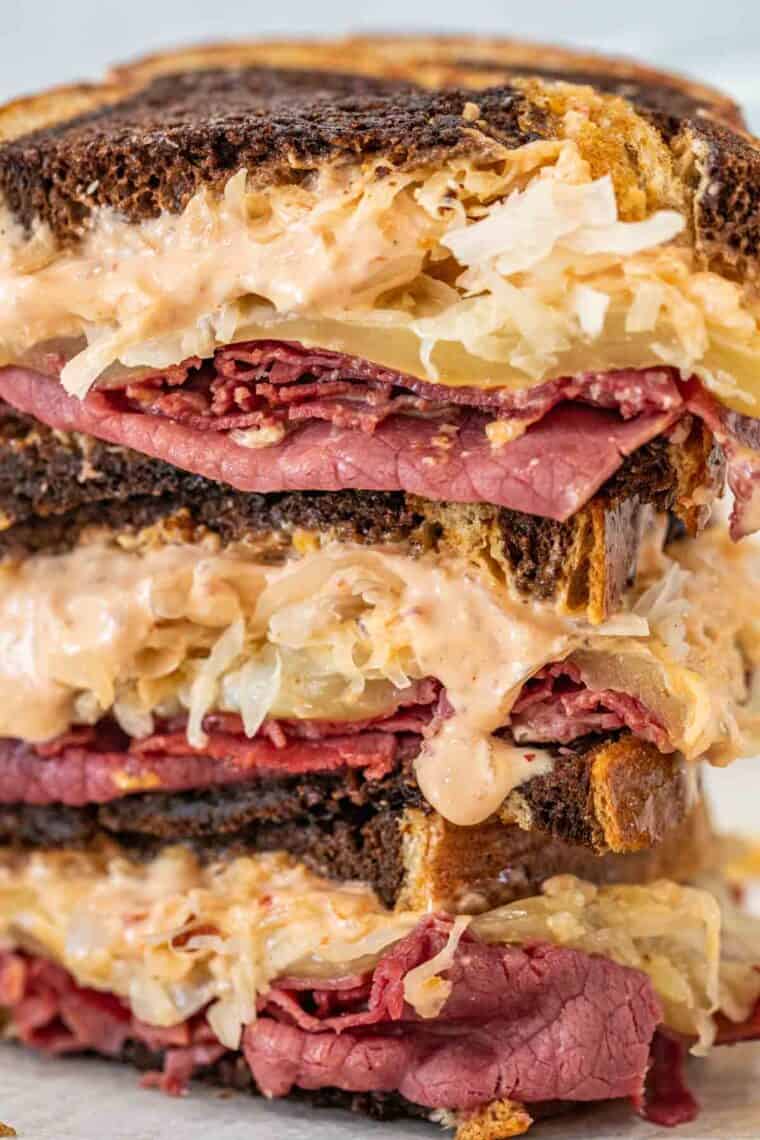 Up close picture of stacked Reuben sandwiches. 