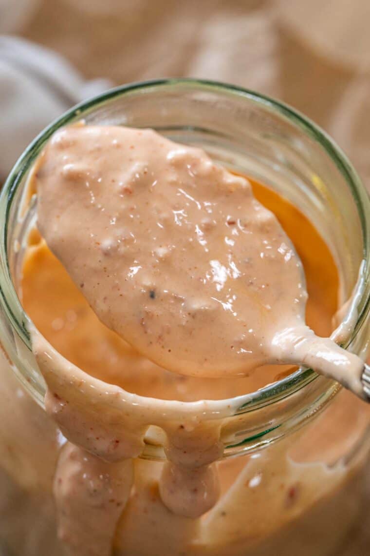 Easy creamy Russian dressing in a mason jar with a spoon full of dressing. 
