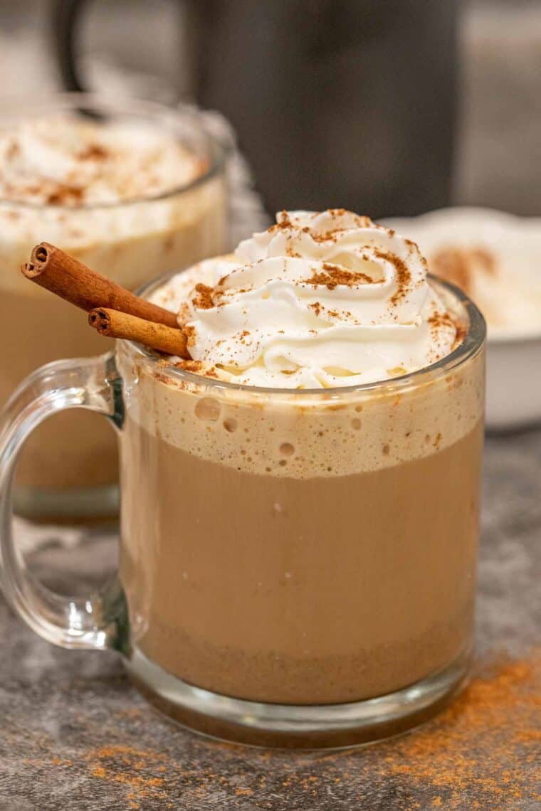 Pumpkin spice latte in a glass mug topped with whipped cream.