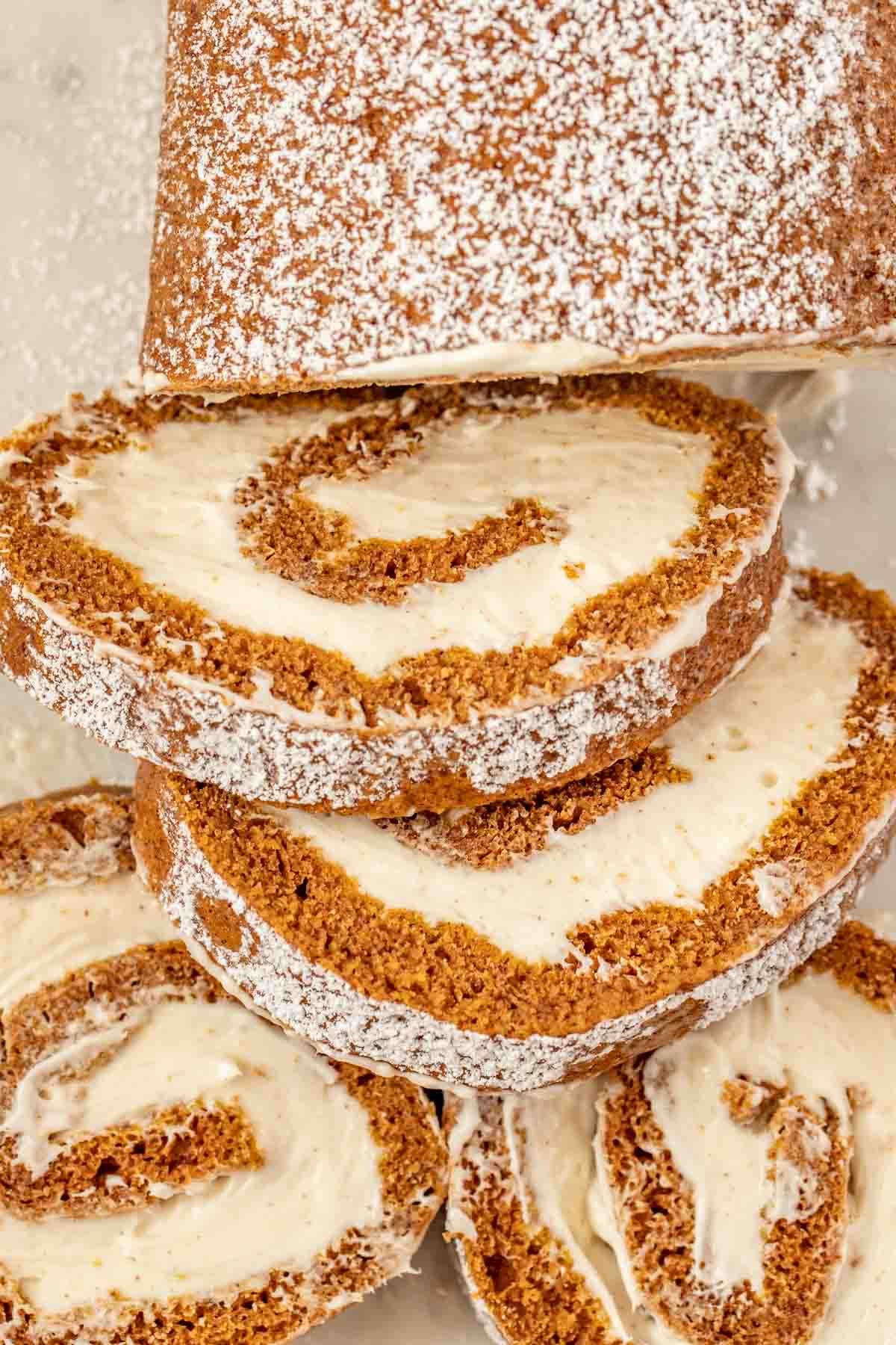 Pumpkin roll with slices on a platter topped with powdered sugar.