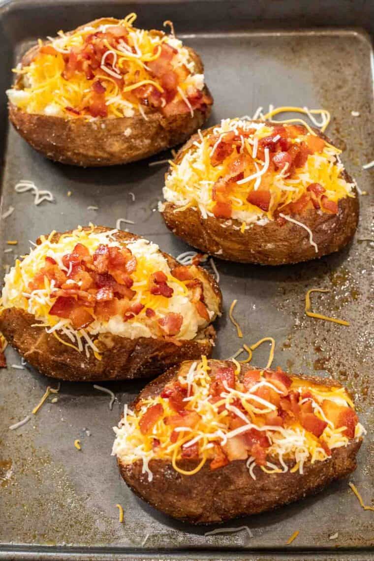 Uncooked stuffed baked potatoes on a baking sheet ready to be baked. 