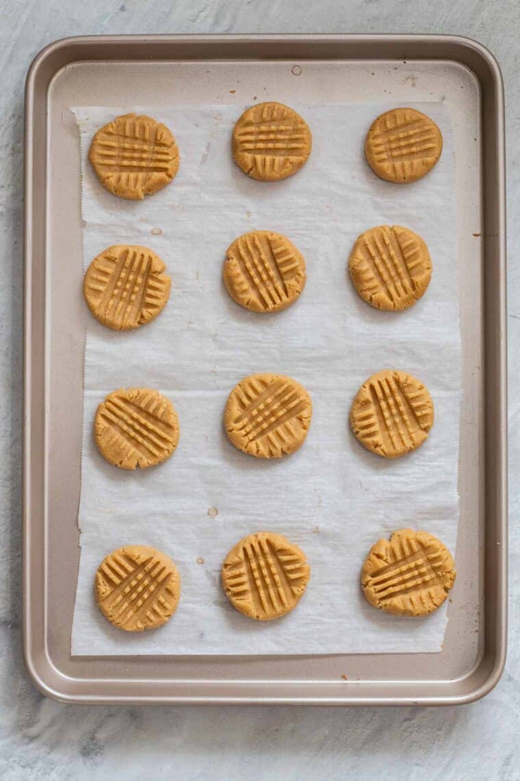 Uncooked peanut butter cookies laid out on a baking sheet. 