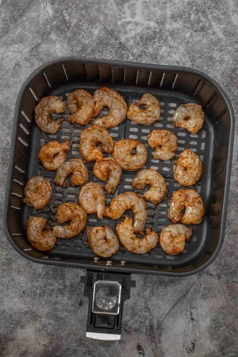 Seasoned shrimp in the air fryer basket ready to be cooked.