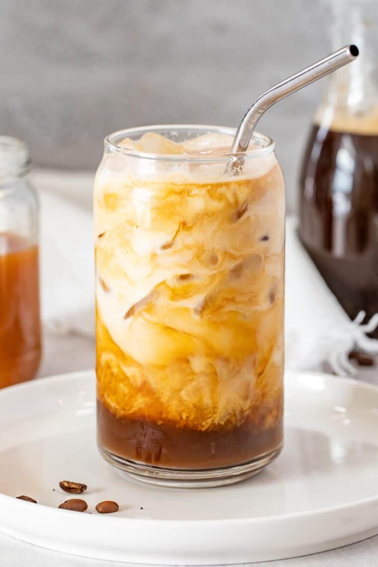 Iced caramel latte in a glass cup on a white plate. 