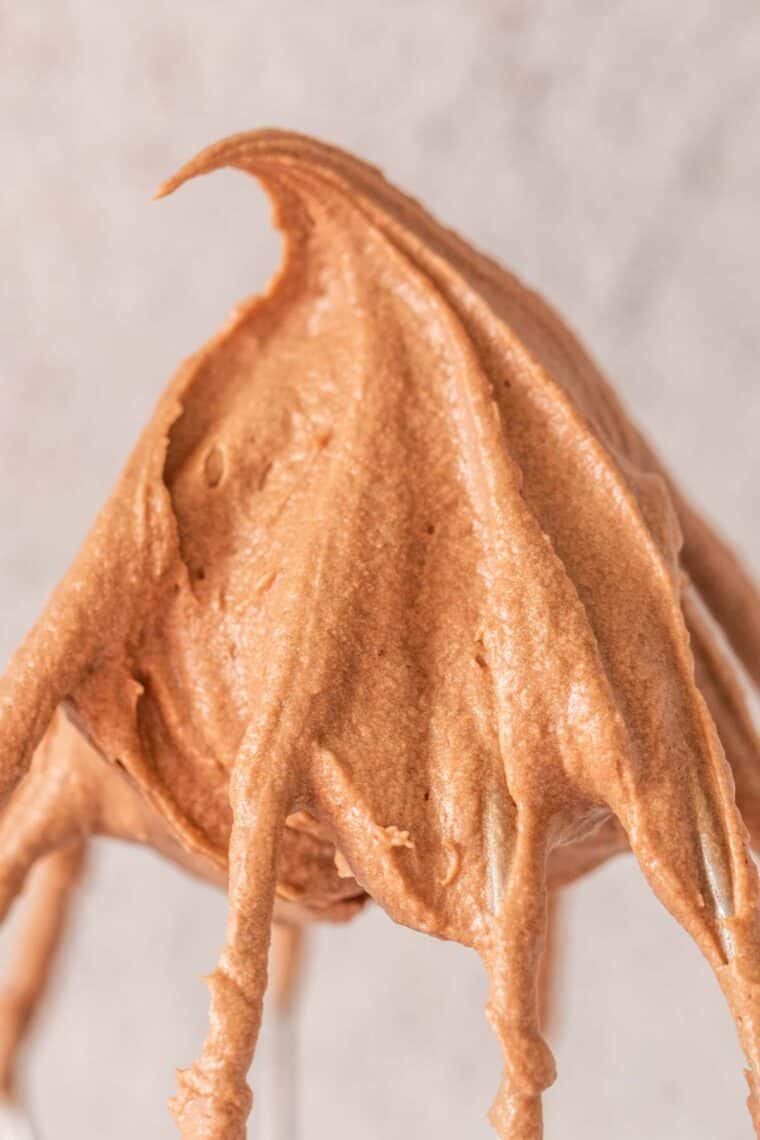 An up close picture of chocolate frosting in mixing whisk.