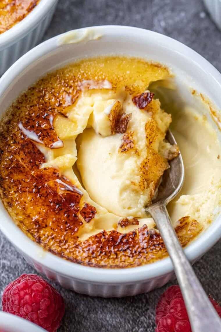 Classic creme brulee in a white ramkein with a spoon. 