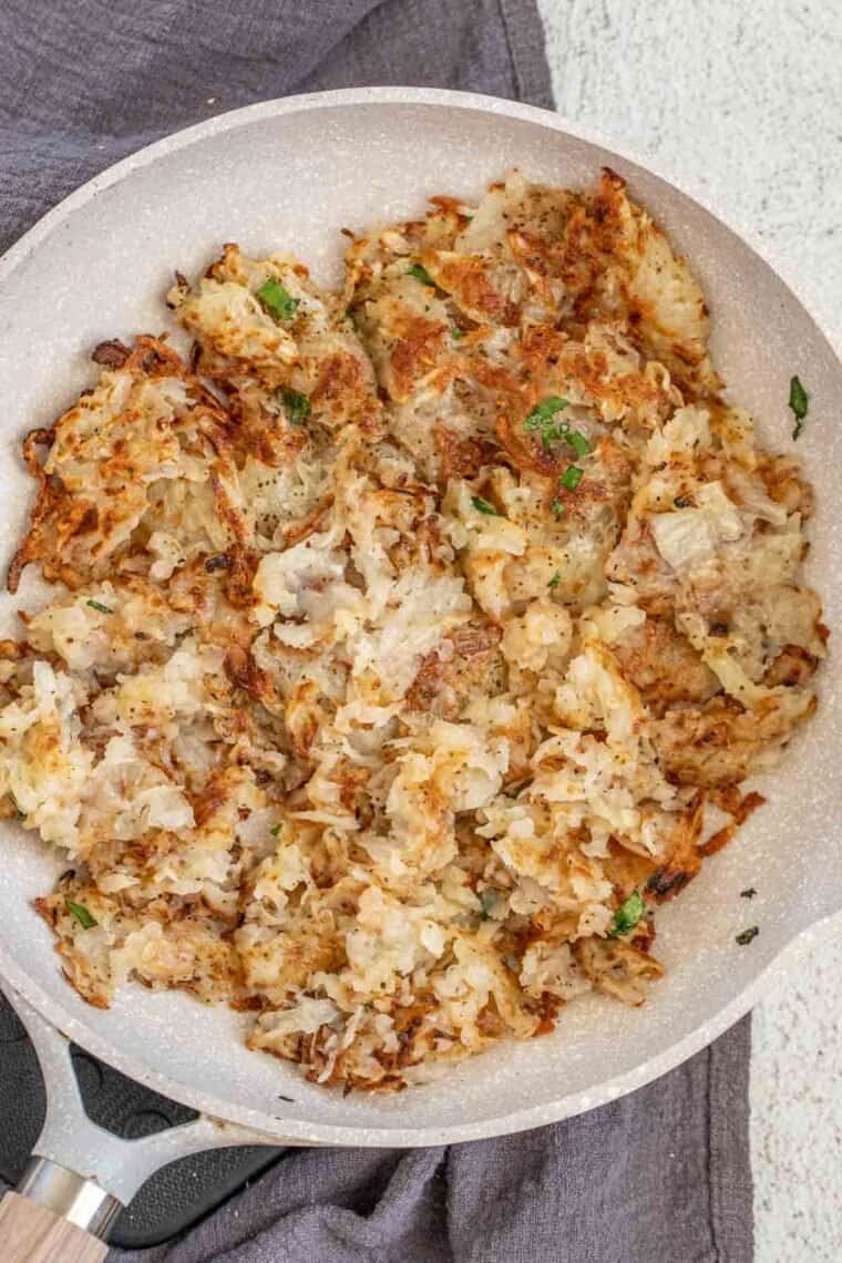 A skillet with loaded shredded potatoes topped with fresh chopped cilantro. 