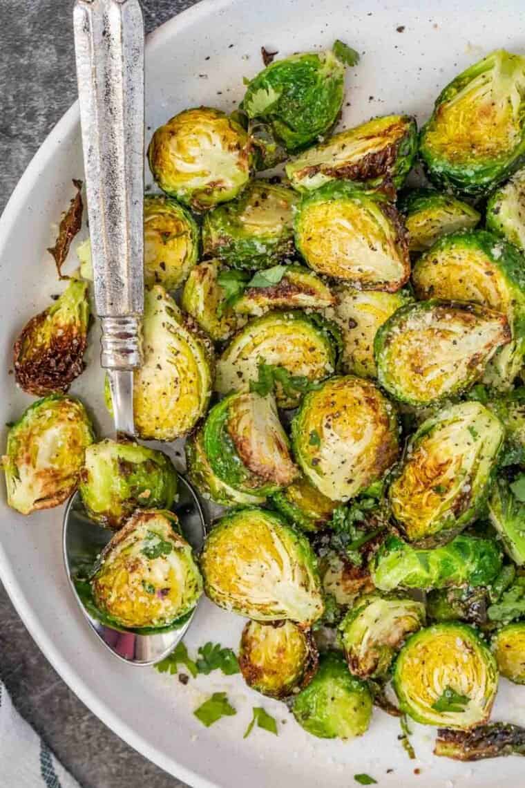 Air fryer brussel sprouts in a bowl with a metal spoon.