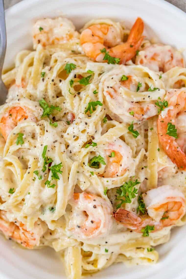 Up close picture of shrimp Alfredo pasta topped with freshly chopped parsley. 