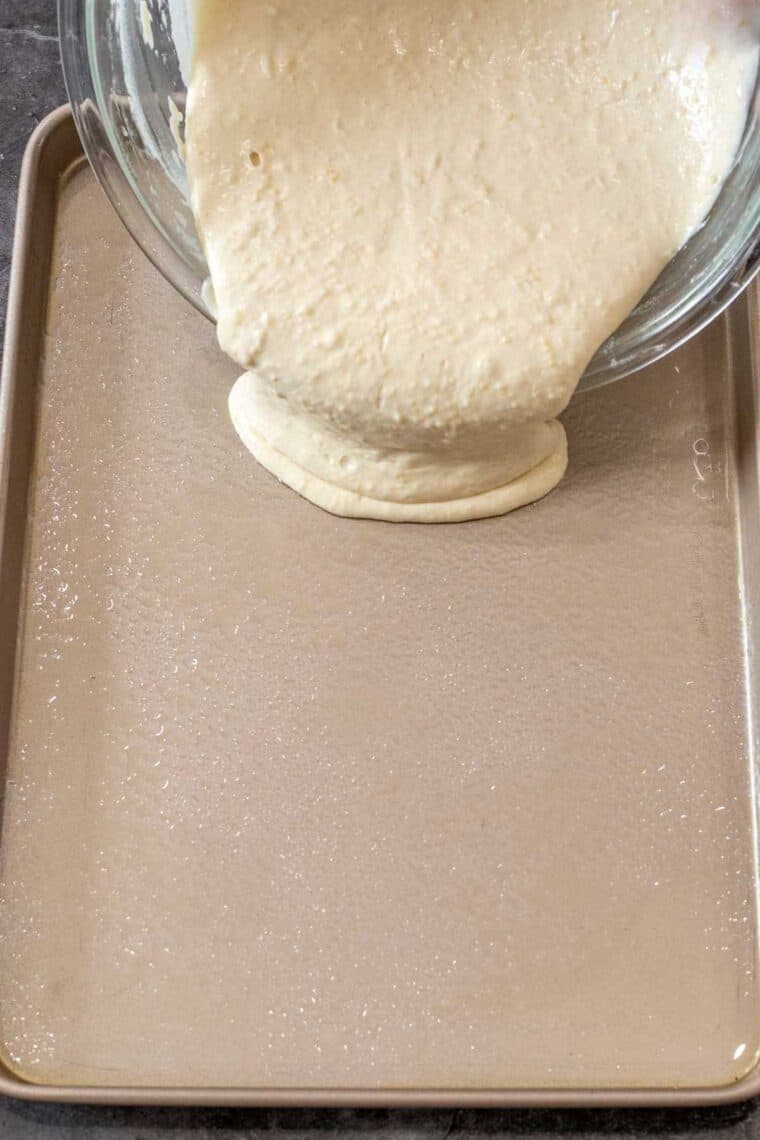Homemade pancake batter begin poured into the baking sheet. 