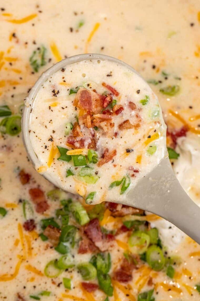 Creamy potato soup in a ladle loaded with bacon and cheese. 