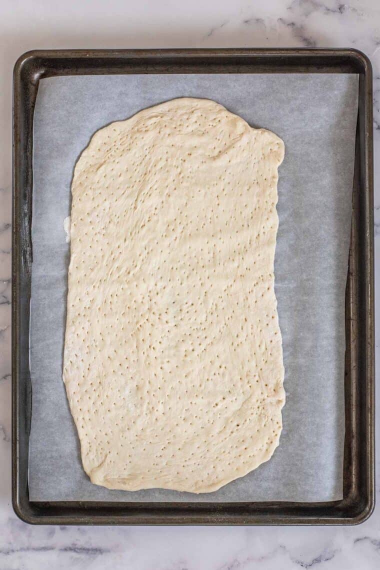 Flatbread dough on a baking sheet with  parchment paper. 