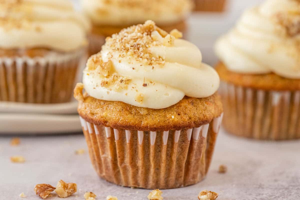 Several cupcakes all topped with frosting and garnished with crushed walnuts.