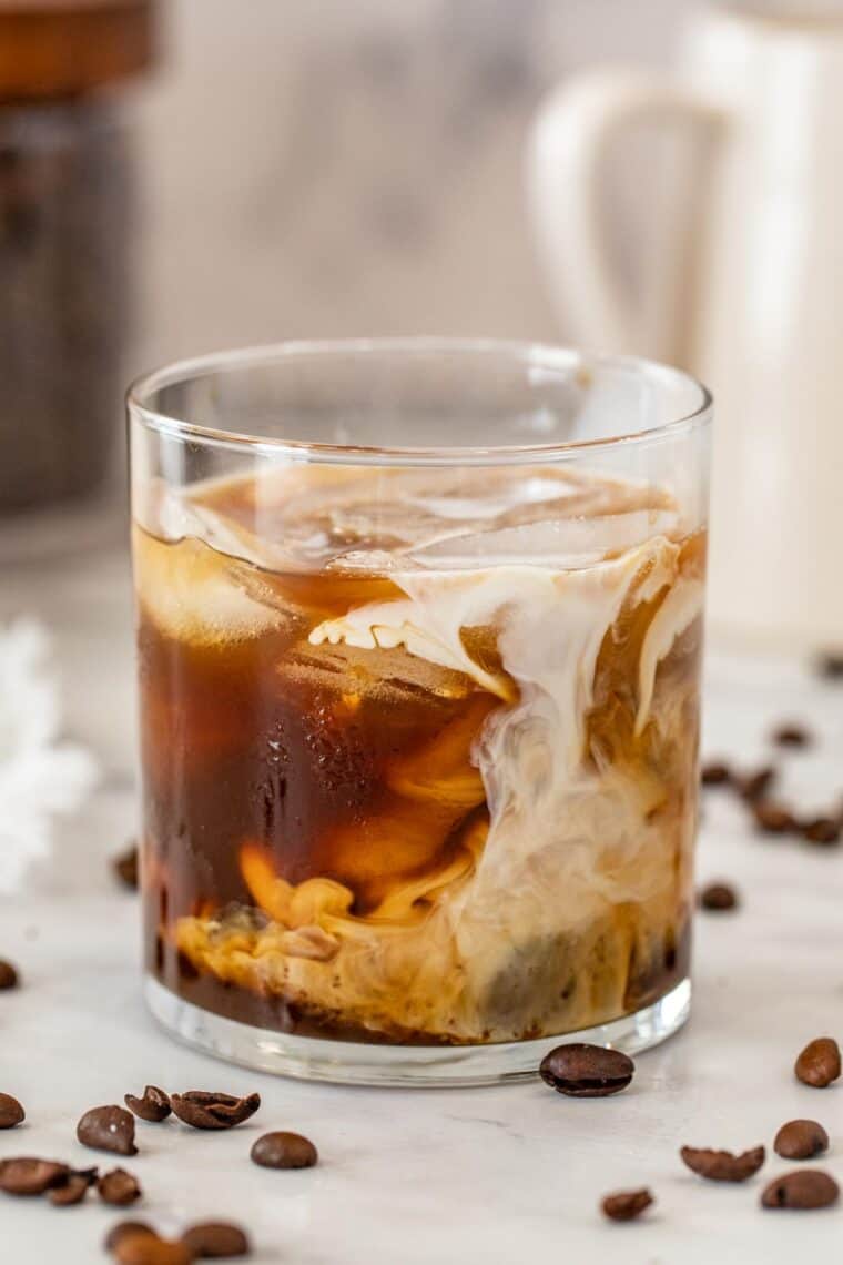 Glass cup with loaded with iced coffee and creamer. 