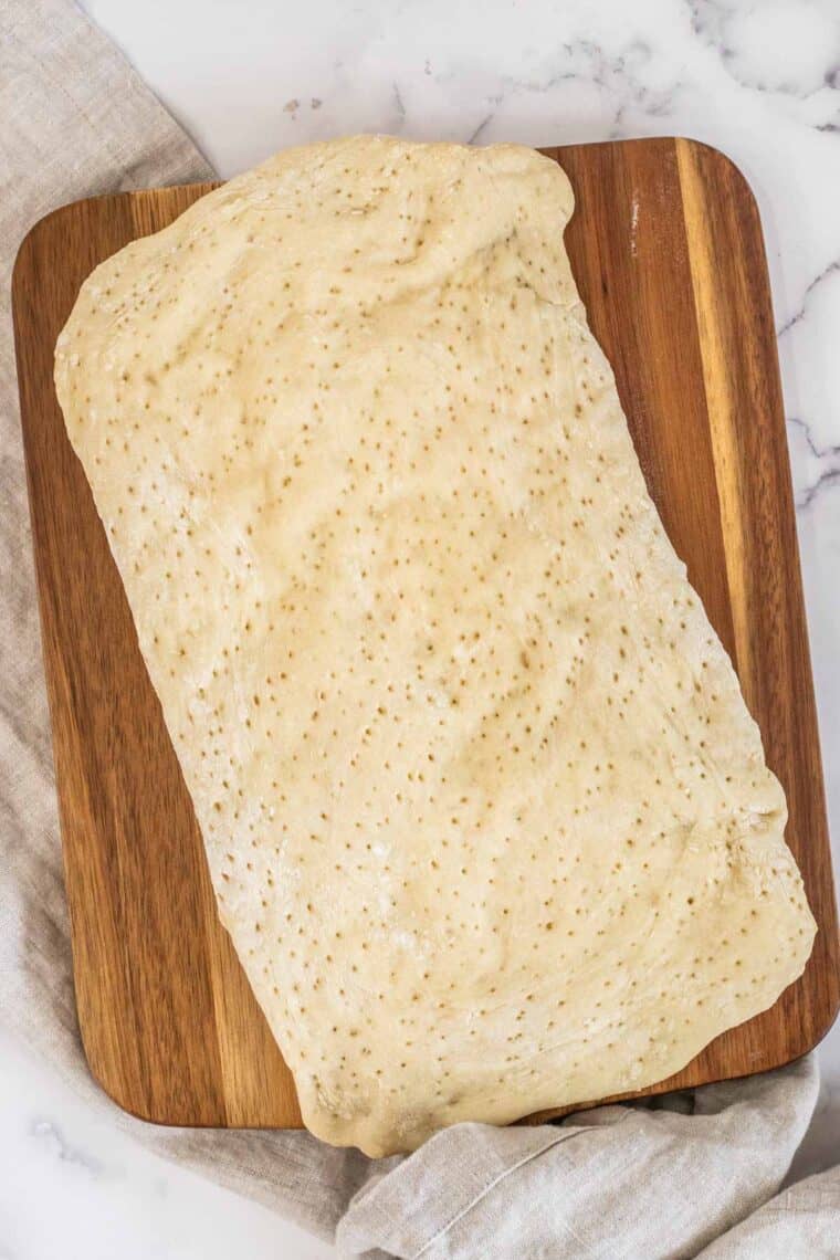 Baked flatbread pizza on a wooden cutting board. 