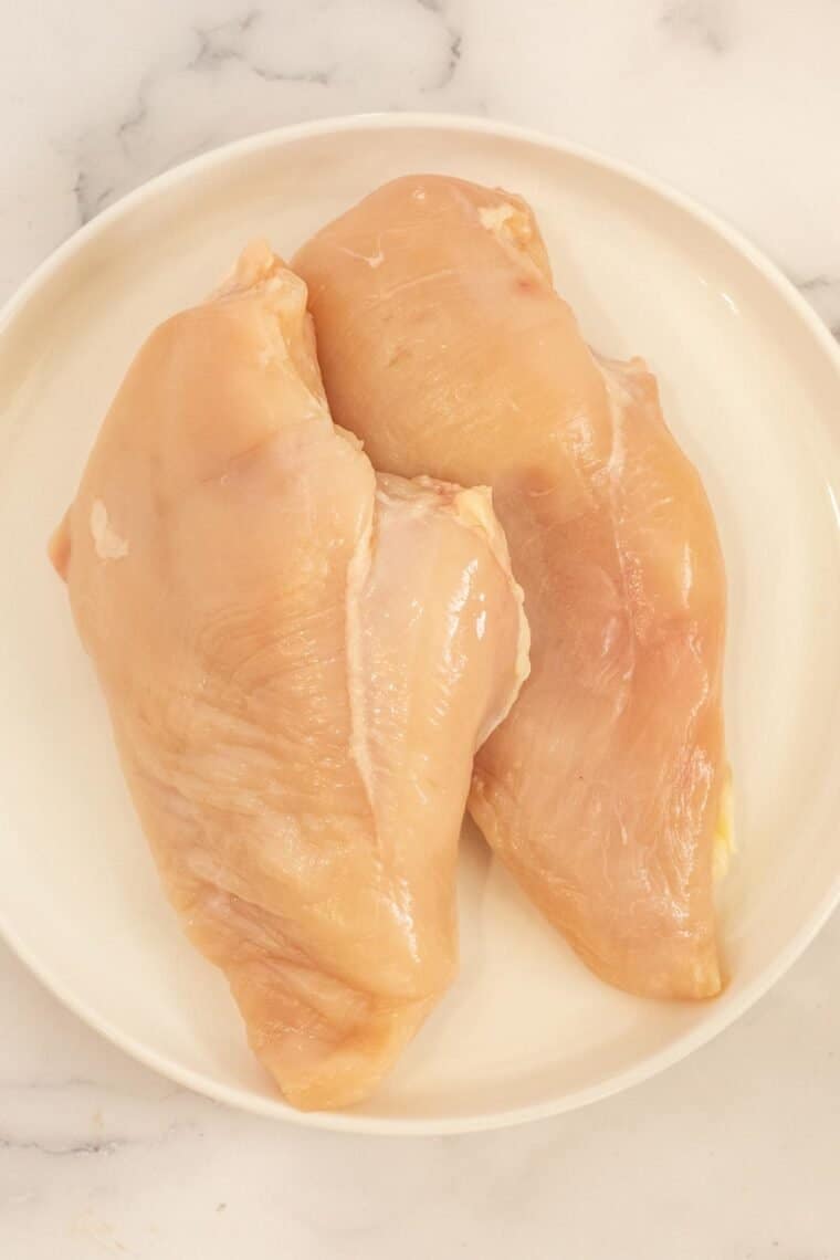 A plate of uncooked chicken breasts. 