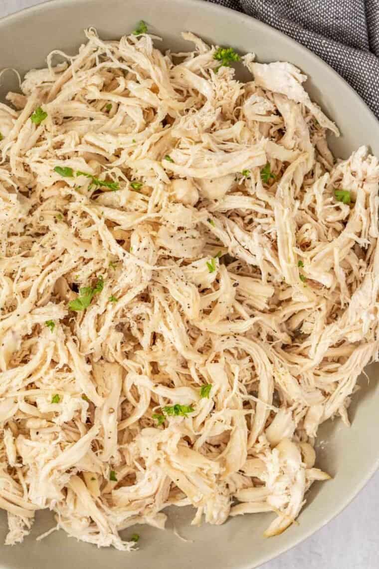 A bowl of shredded chicken topped with fresh greens and black pepper. 