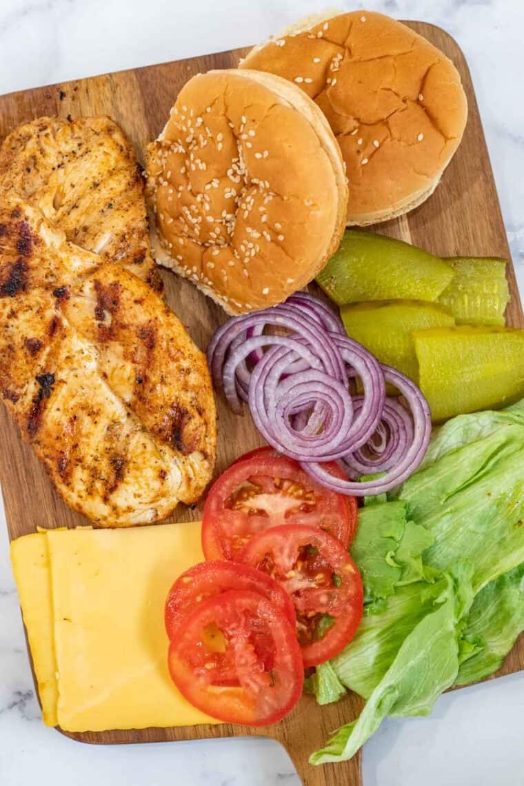 All the ingredients needed for the grilled chicken sandwiches on a cutting board. 