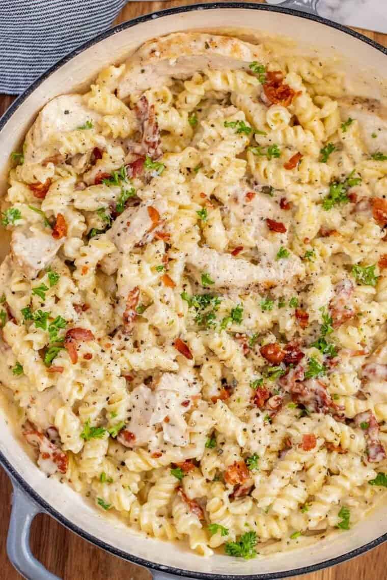 Chicken bacon Ranch pasta in a deep skillet topped with bacon and chopped parsley. 