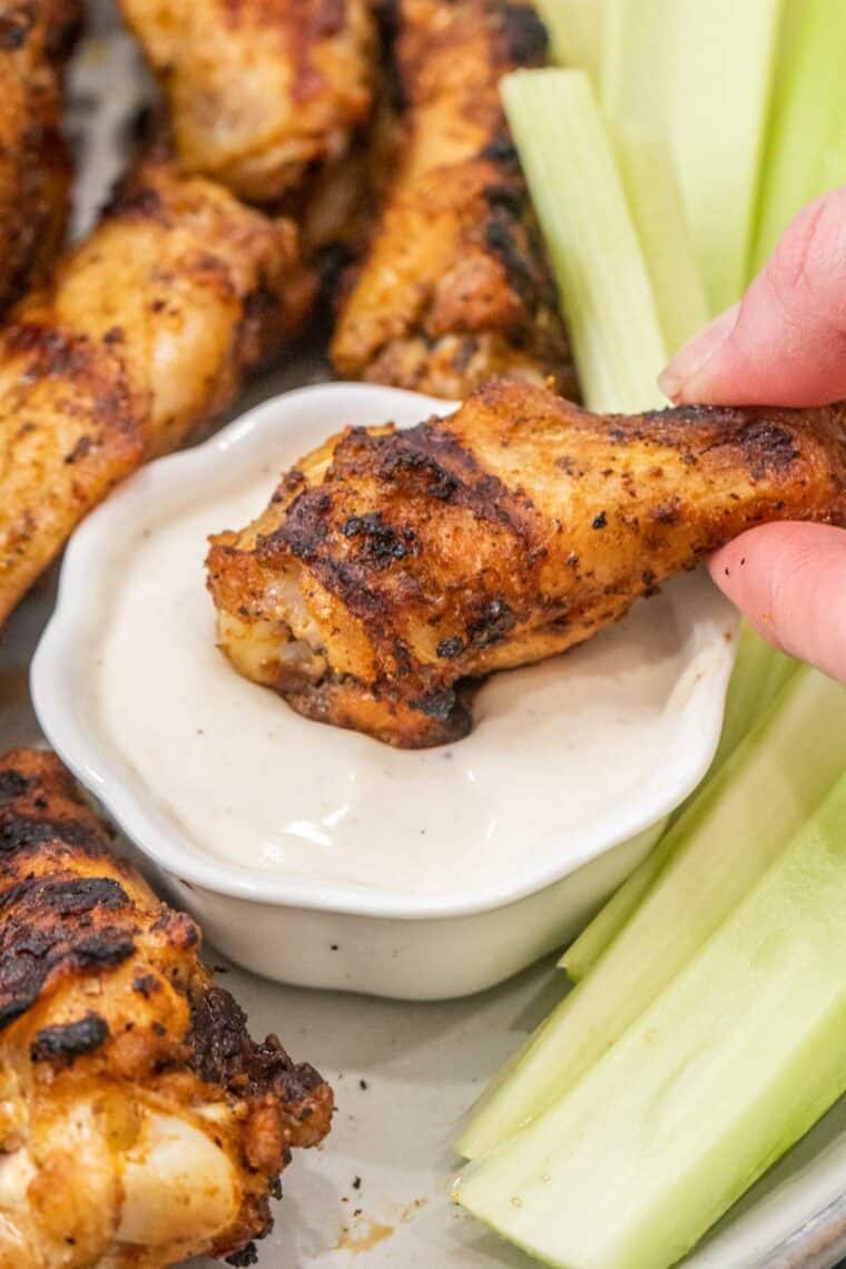 Chicken wing being dipped into ranch. 
