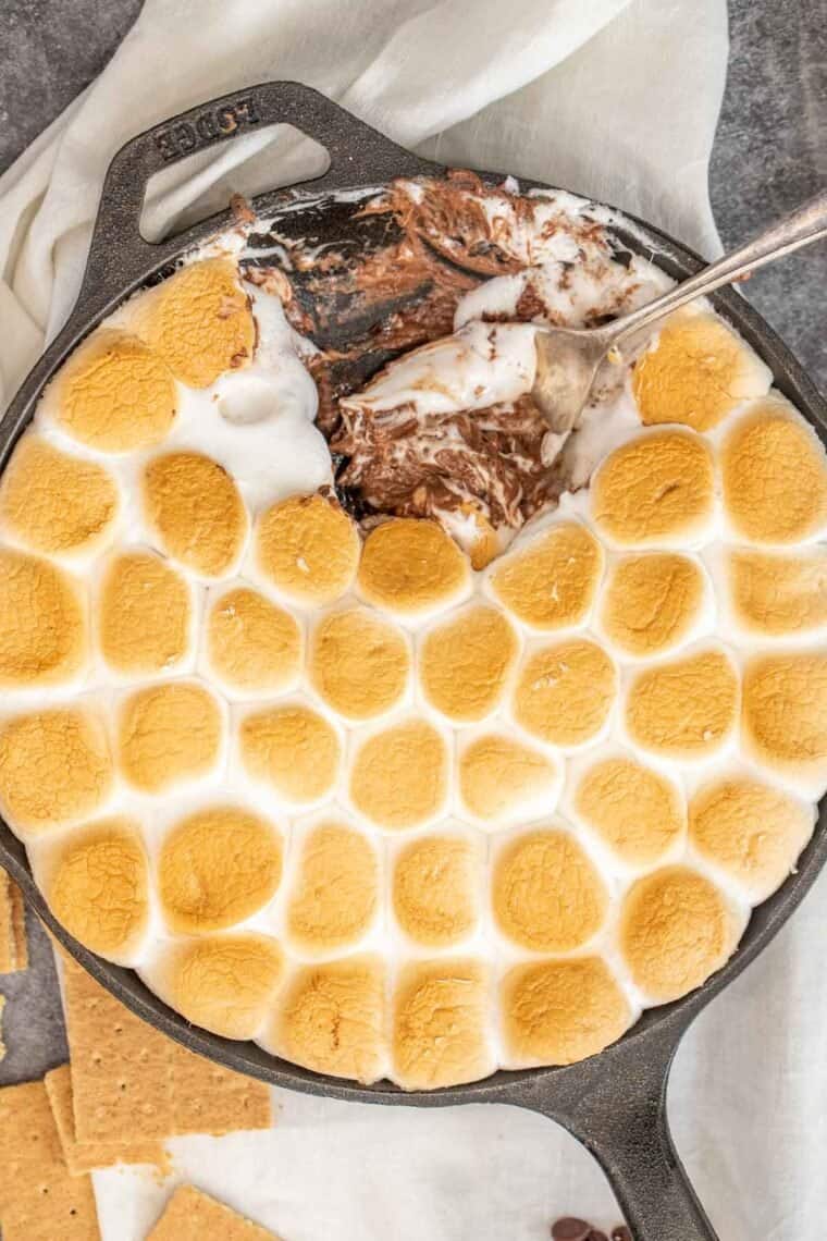Cast iron dish with smores dip with a spoon. 