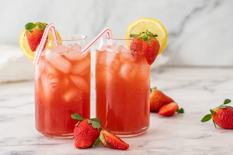 Strawberry acai lemonade in two glass cups with straws. 