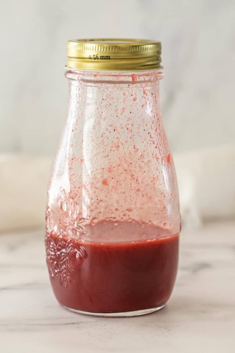 A glass bottle of strawberry acai syrup. 