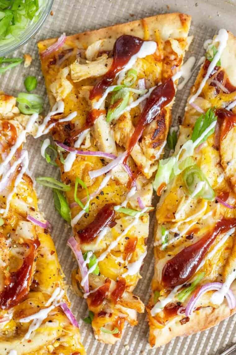 A slice of bbq chicken flatbread drizzled with ranch and bbq. 