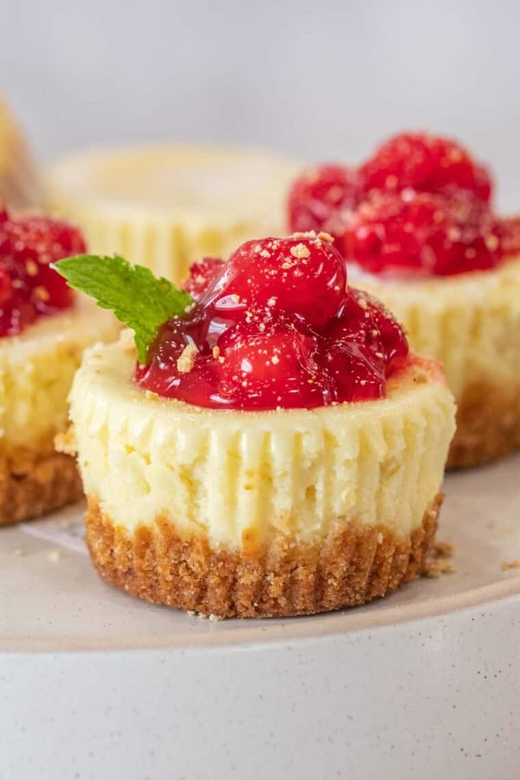 Cheesecake bites topped with cherry pie filling on a plate.