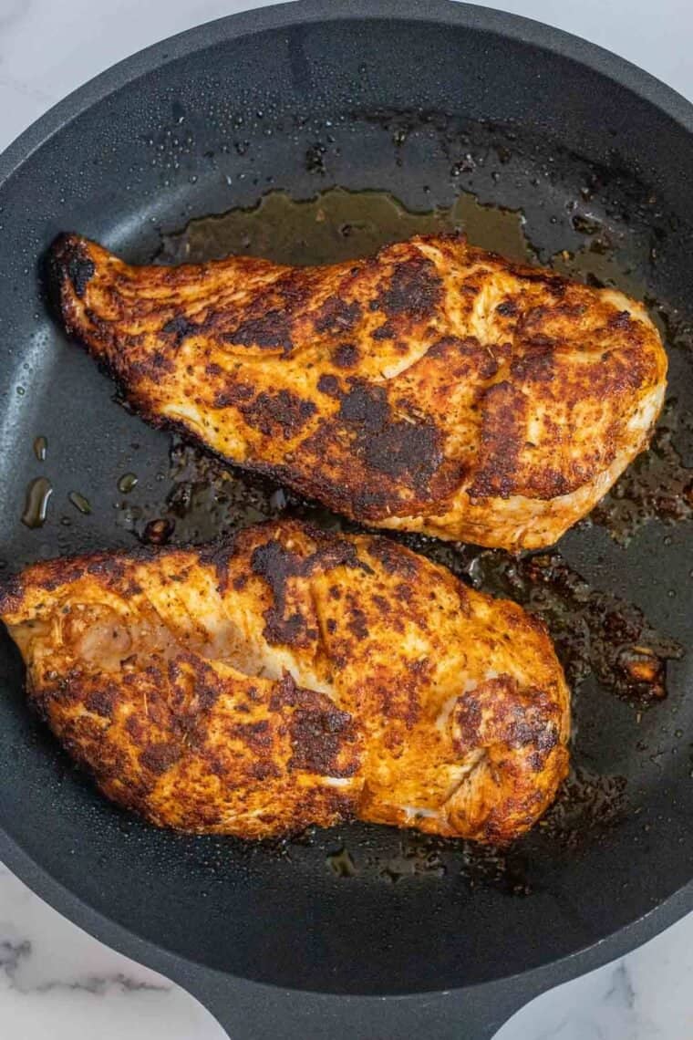 Chicken breast sauteed in a black skillet. 
