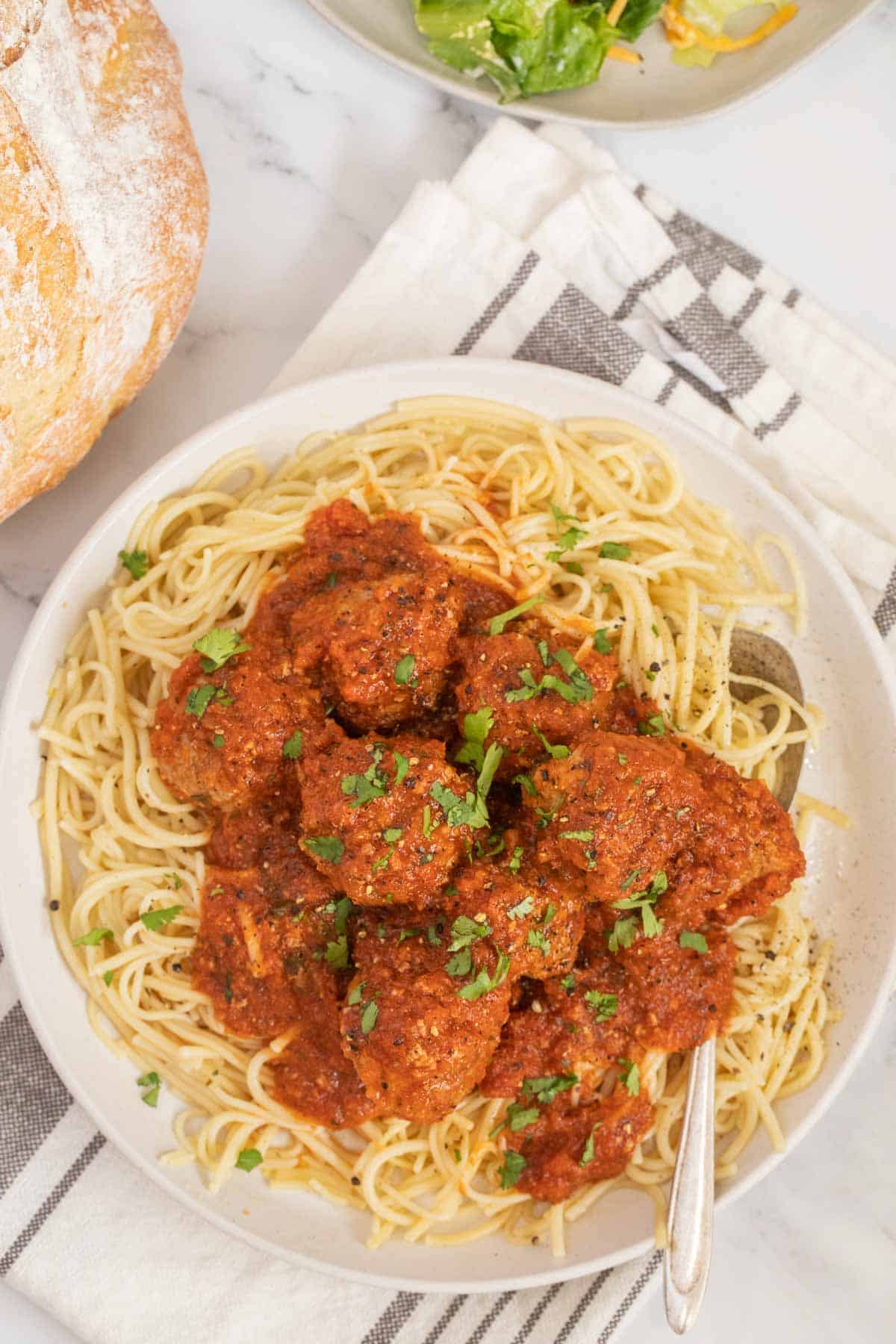 Instant pot meatballs over a bed of pasta on a white plate. 