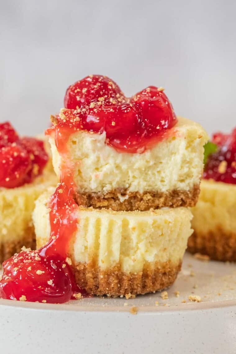 Two cheesecake bites stacked on top of each other with cherry pie filling. 