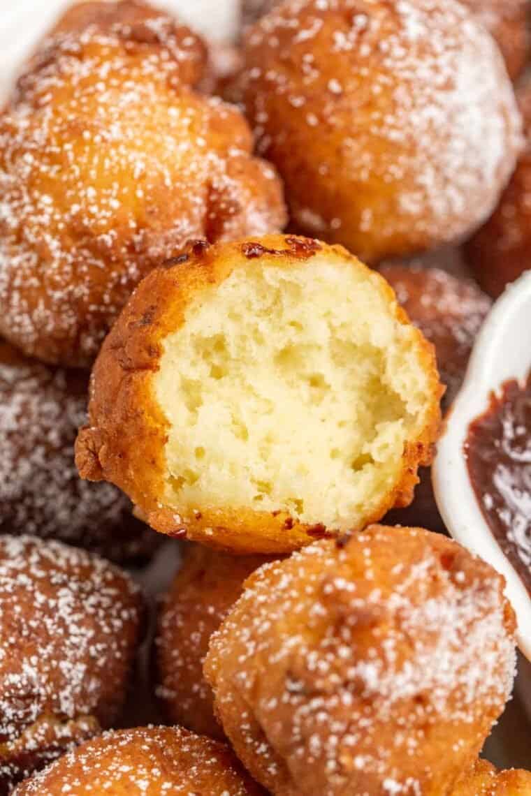 Soft ricotta donuts bitten into topped with powdered sugar. 