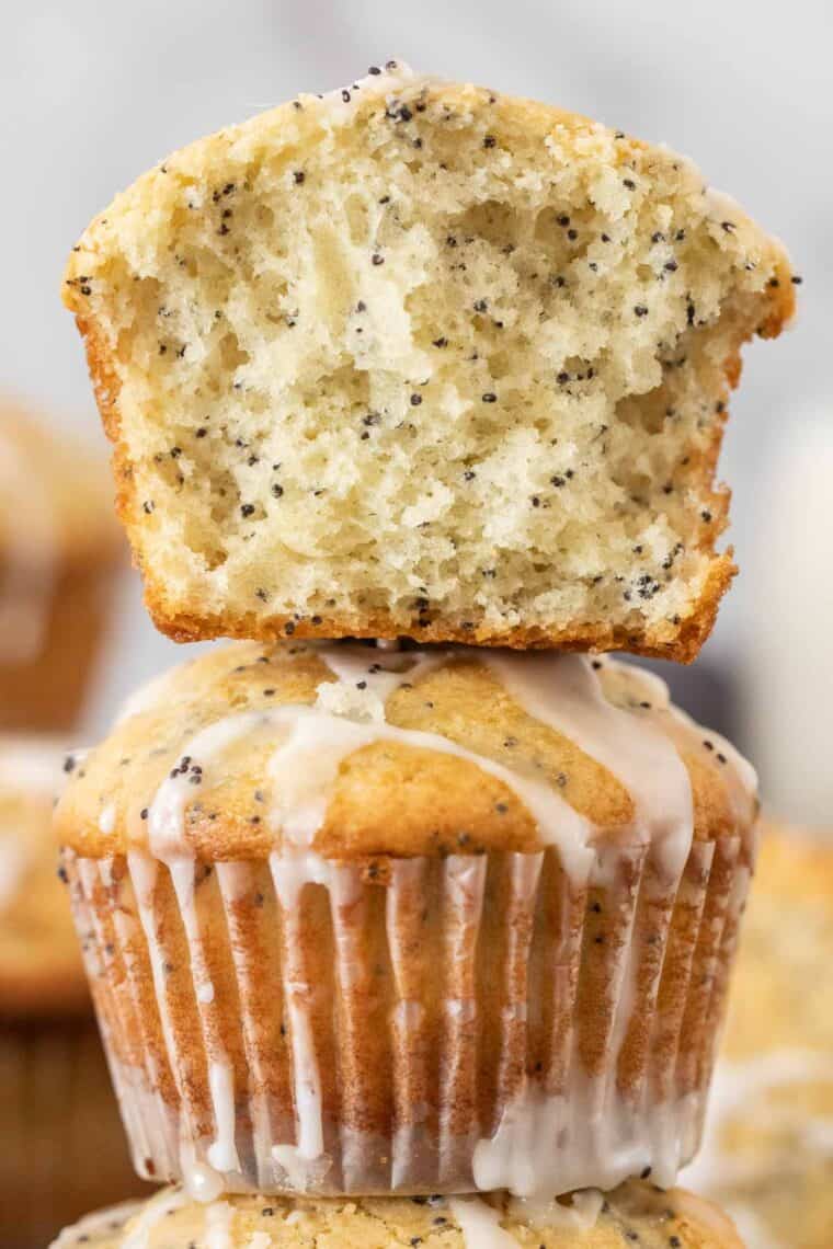 Poppyseed muffins stacked on top of each other with a half of muffin on top. 