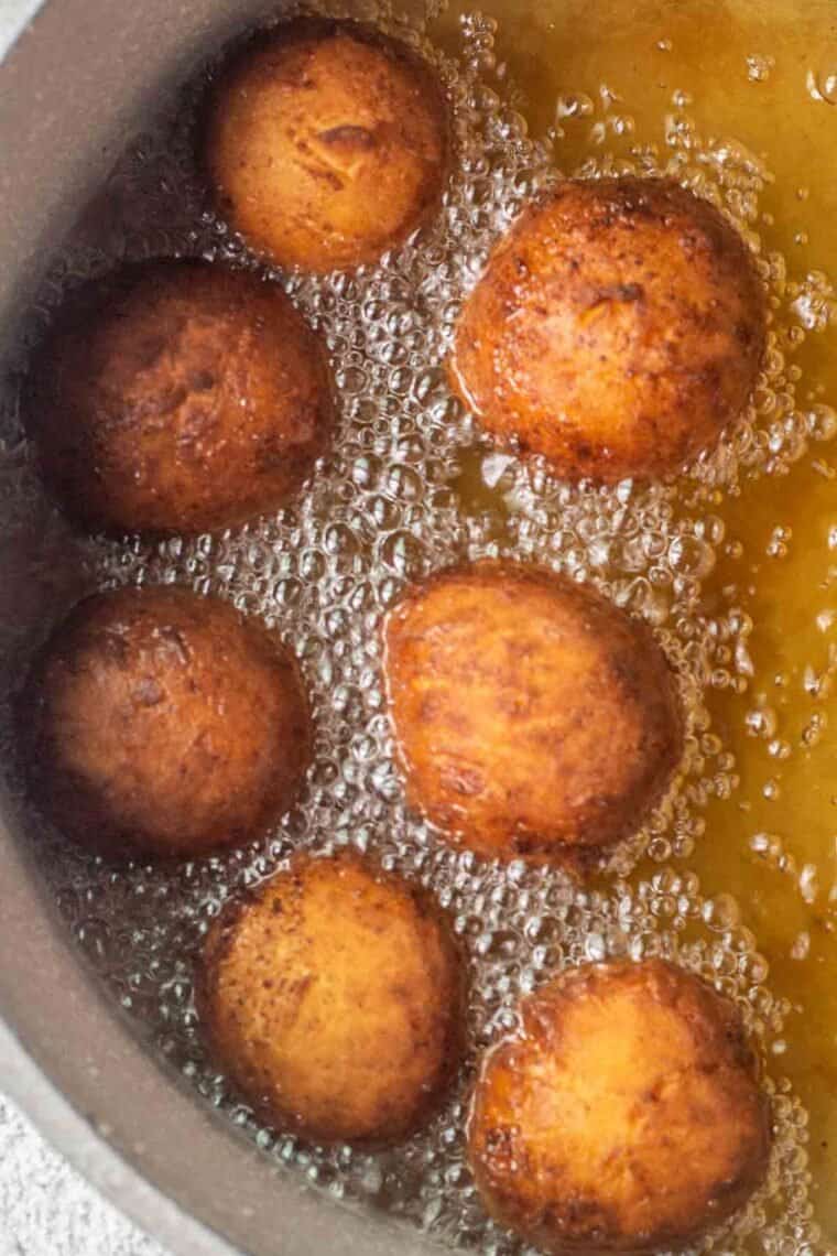 Ricotta donut holes in oil being fried. 