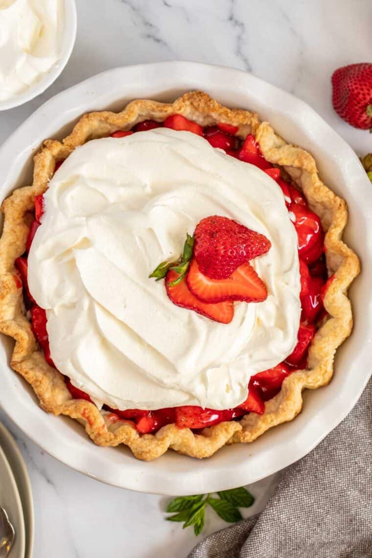 Strawberry pie topped with whipped cream and fresh strawberry slices. 