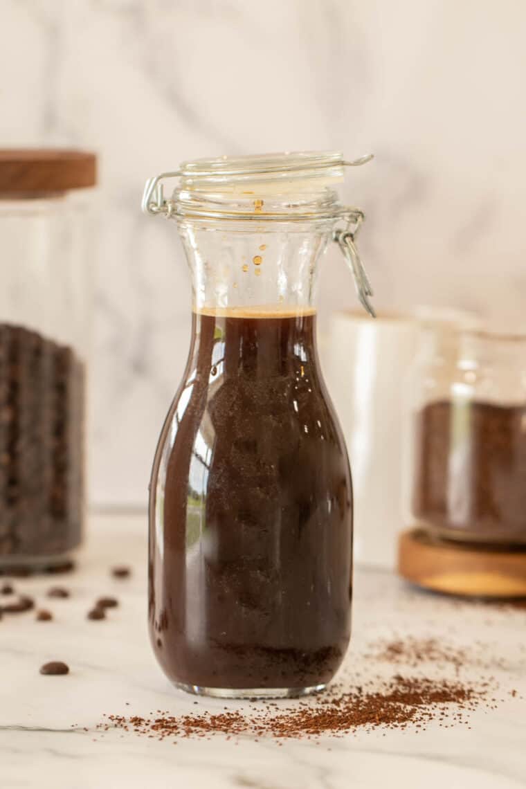 Cold brew coffee in a jar next to coffee grounds. 