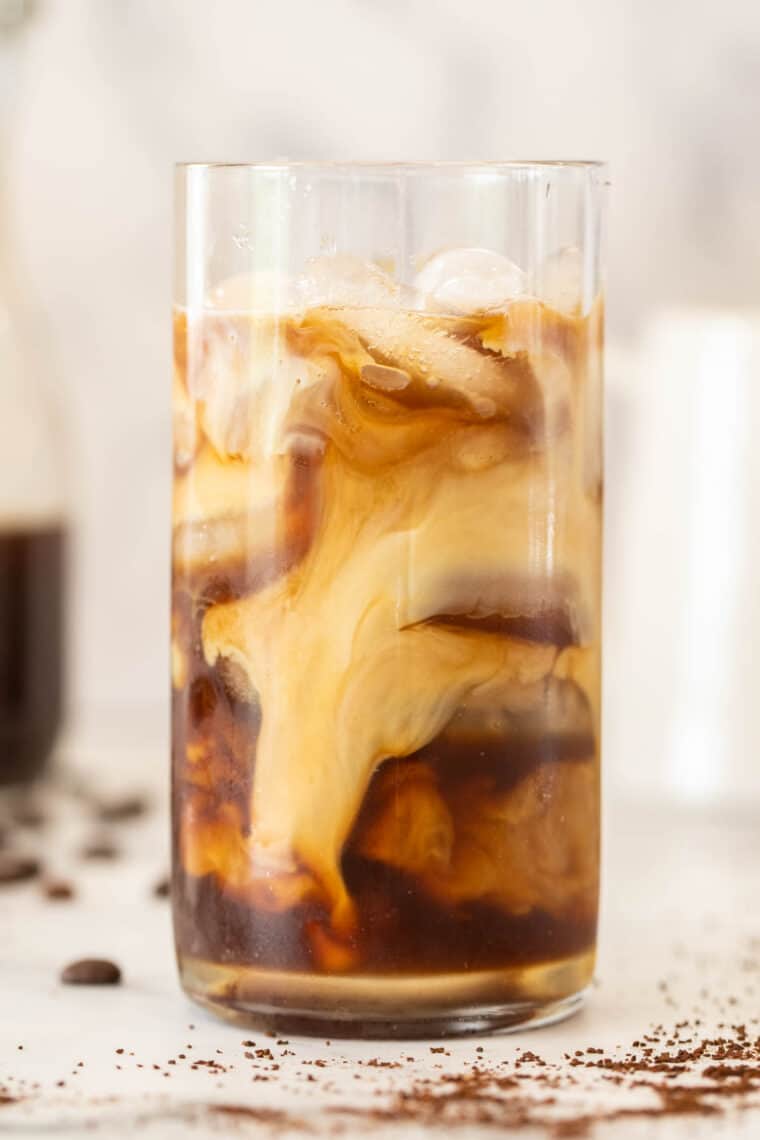 A glass of cold brew coffee with ice and creamer. 